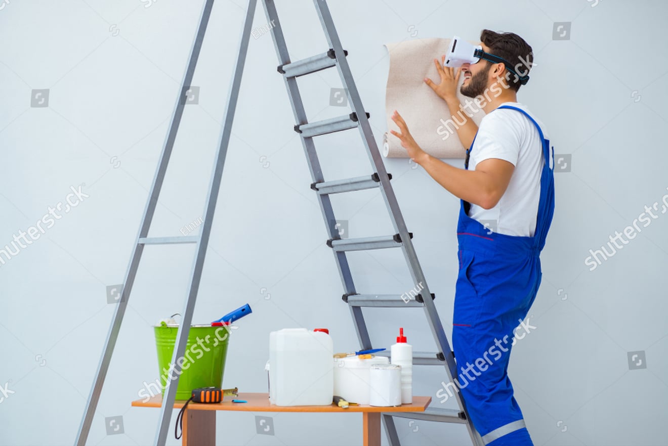Man hanging wallpaper while wearing VR headset